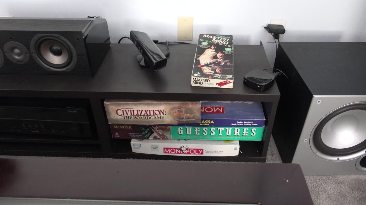 Black media shelf with stereo speakers, board games, and audio equipment.