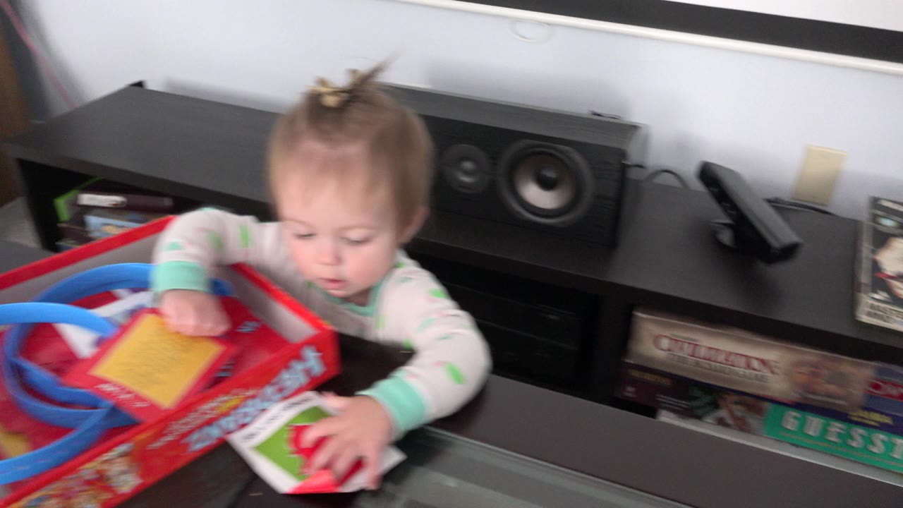 Baby girl reaching into a red tabletop game box.