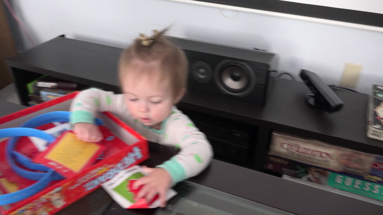 The child leans over the red game box while blue looped pieces and illustrated cards fill the foreground of the Westminster home interior.