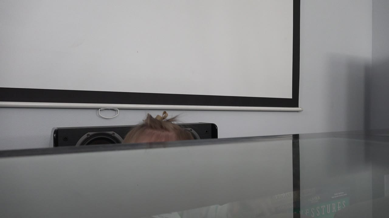 At 0:01, the baby remains mostly hidden below the reflective tabletop edge, with only hair and part of the forehead visible below the white screen in the Westminster, Colorado interior.