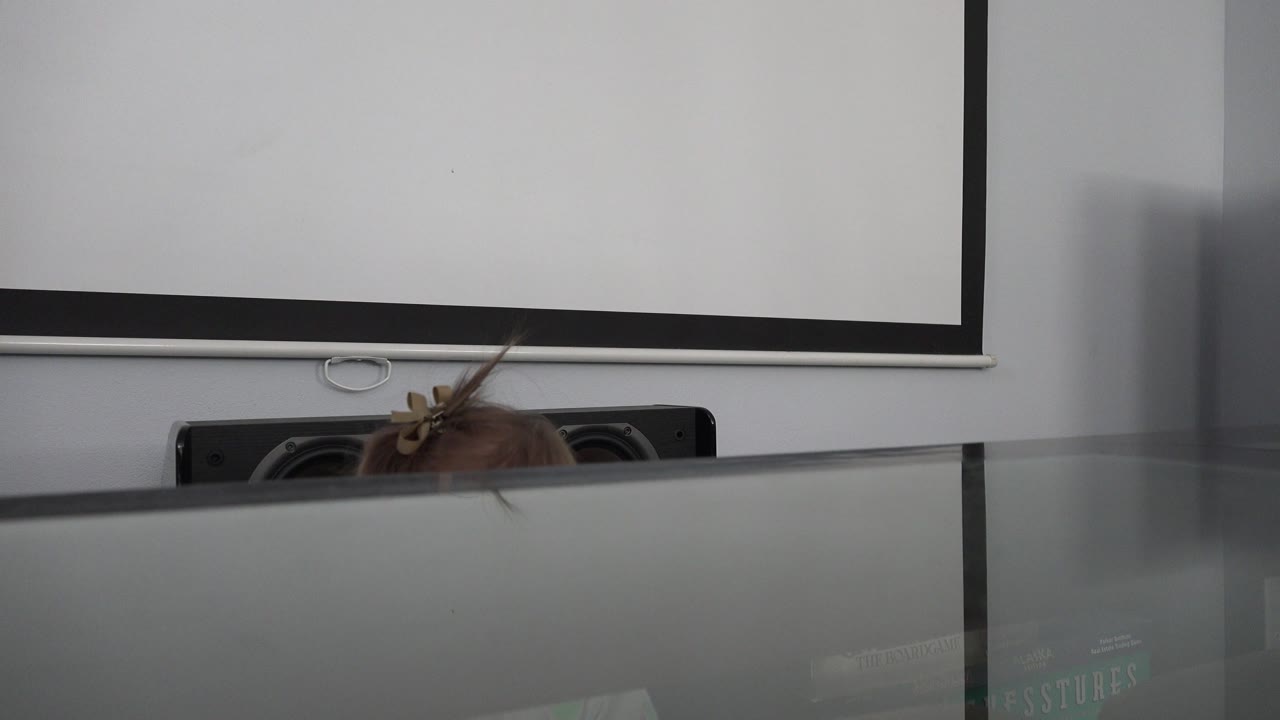 Toddler's hair and bow barely visible behind a grey indoor screen.