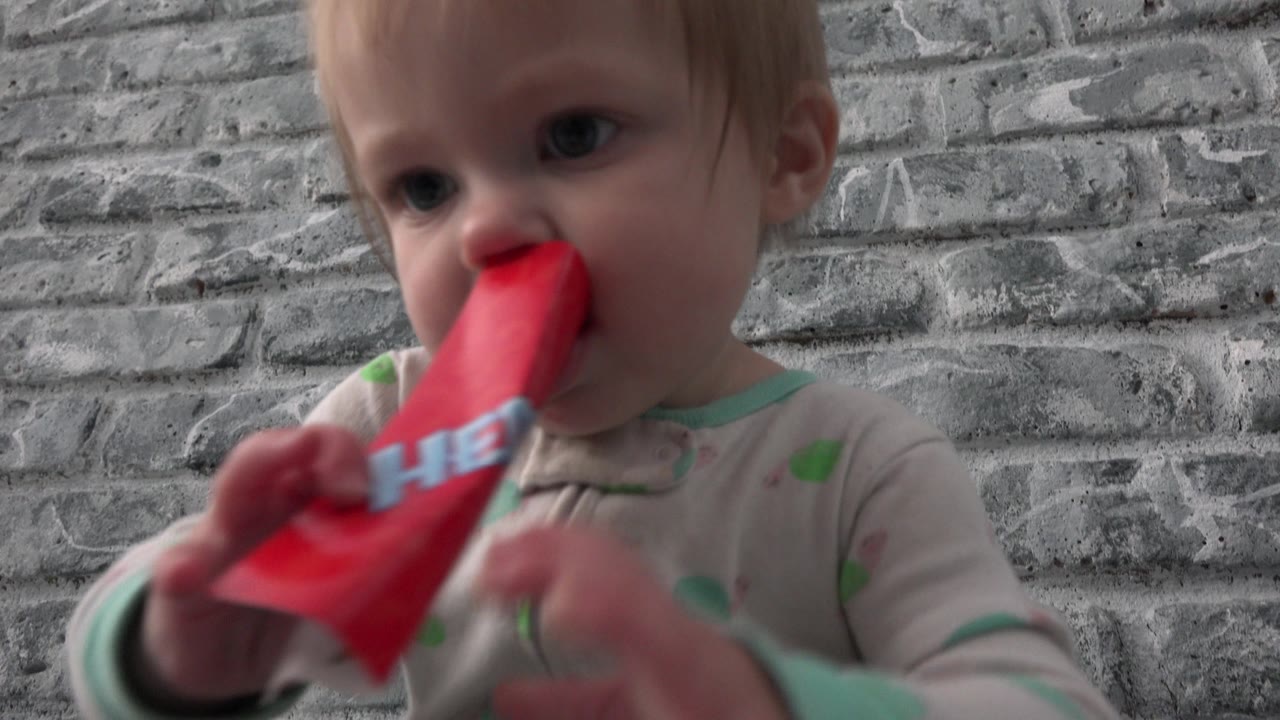 Close view of baby mouthing a red paper toy.