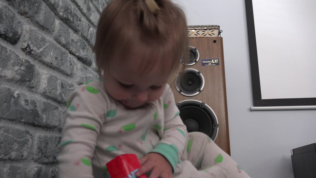 Child looks down toward a red wrapper in their hands.