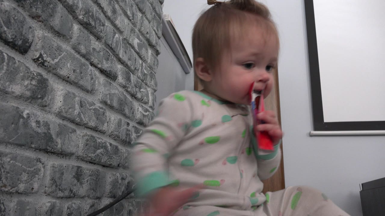 The baby continues chewing the paper in the Westminster, Colorado home setting, with one hand blurred from movement near the lower frame.