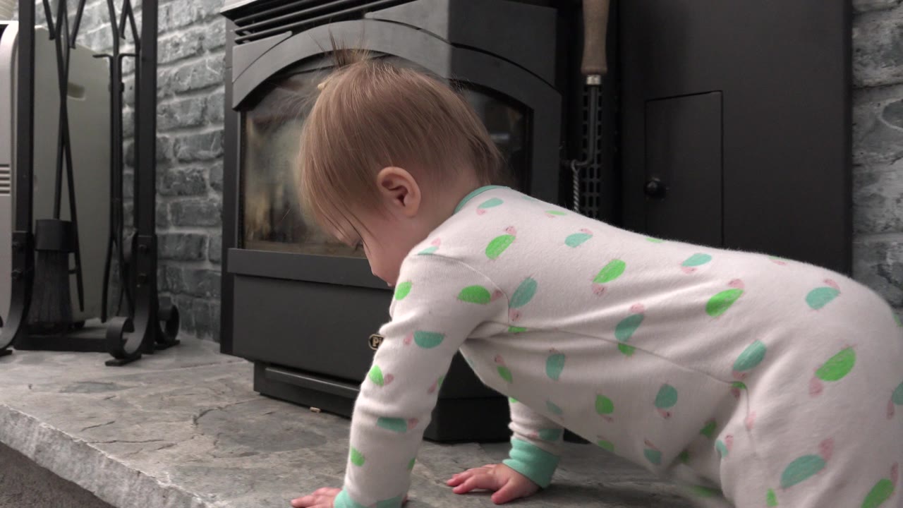 At 0:01 in Westminster, Colorado, the baby continues crawling with one hand near the raised concrete edge, framed against the closed dark door and stone background.