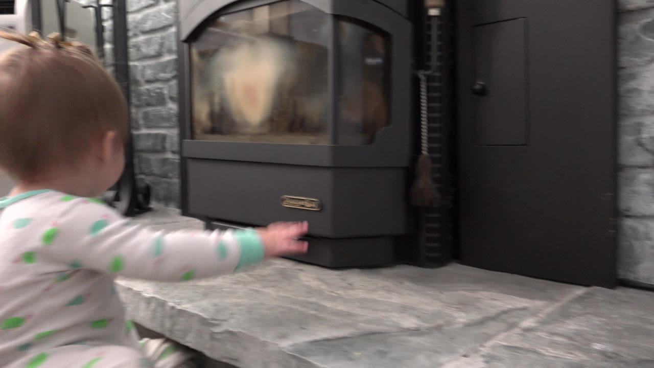 Baby crawling toward a black fireplace on a gray hearth.