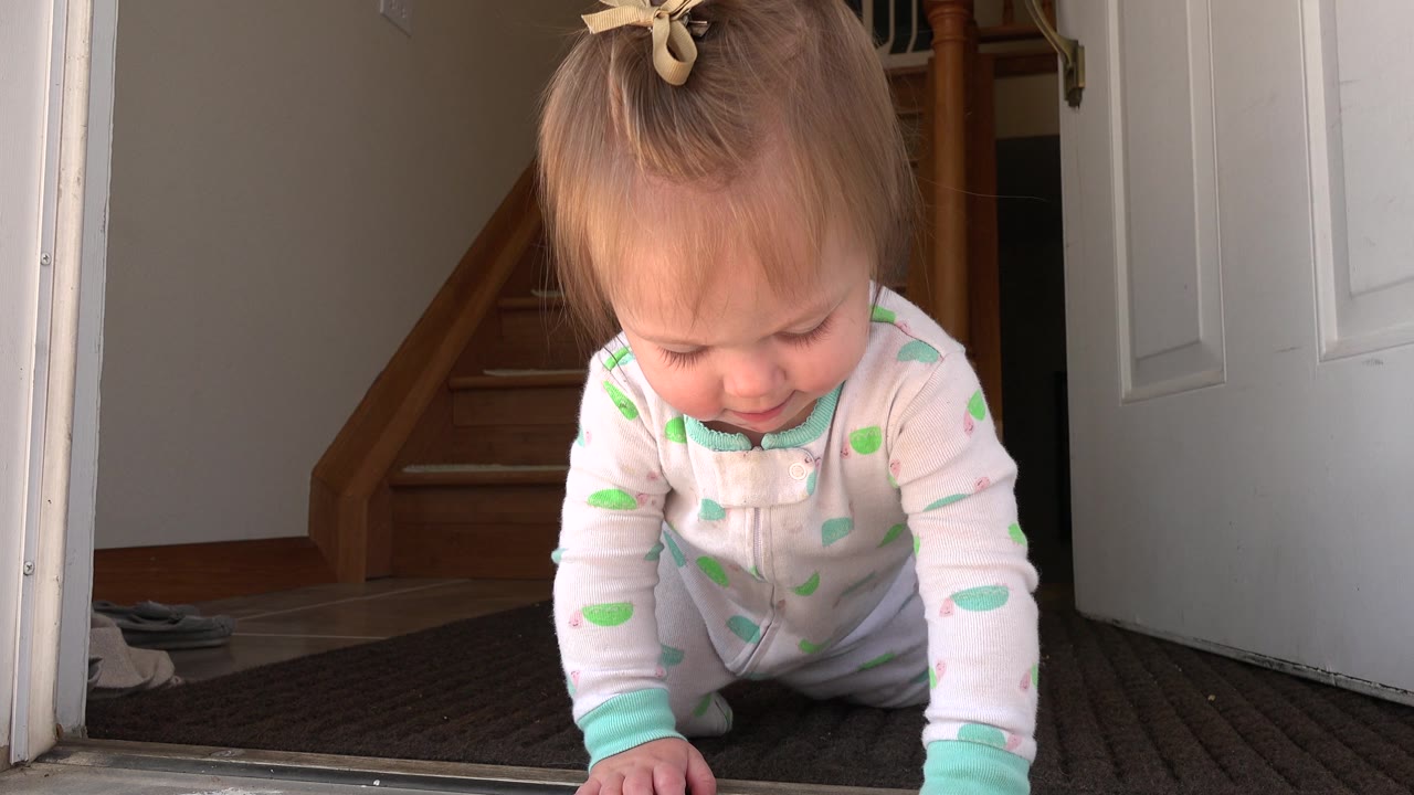 Baby girl crawling with one hand forward near the door threshold.