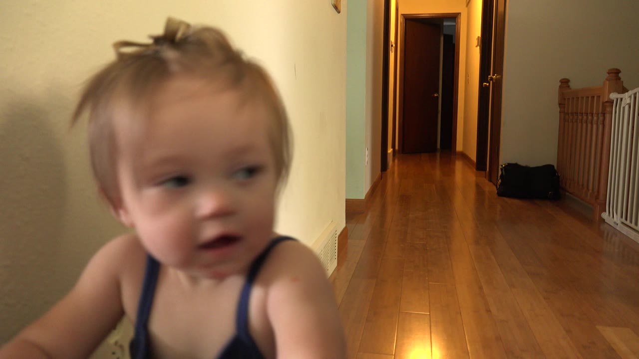 Toddler close to camera beside a wooden hallway.