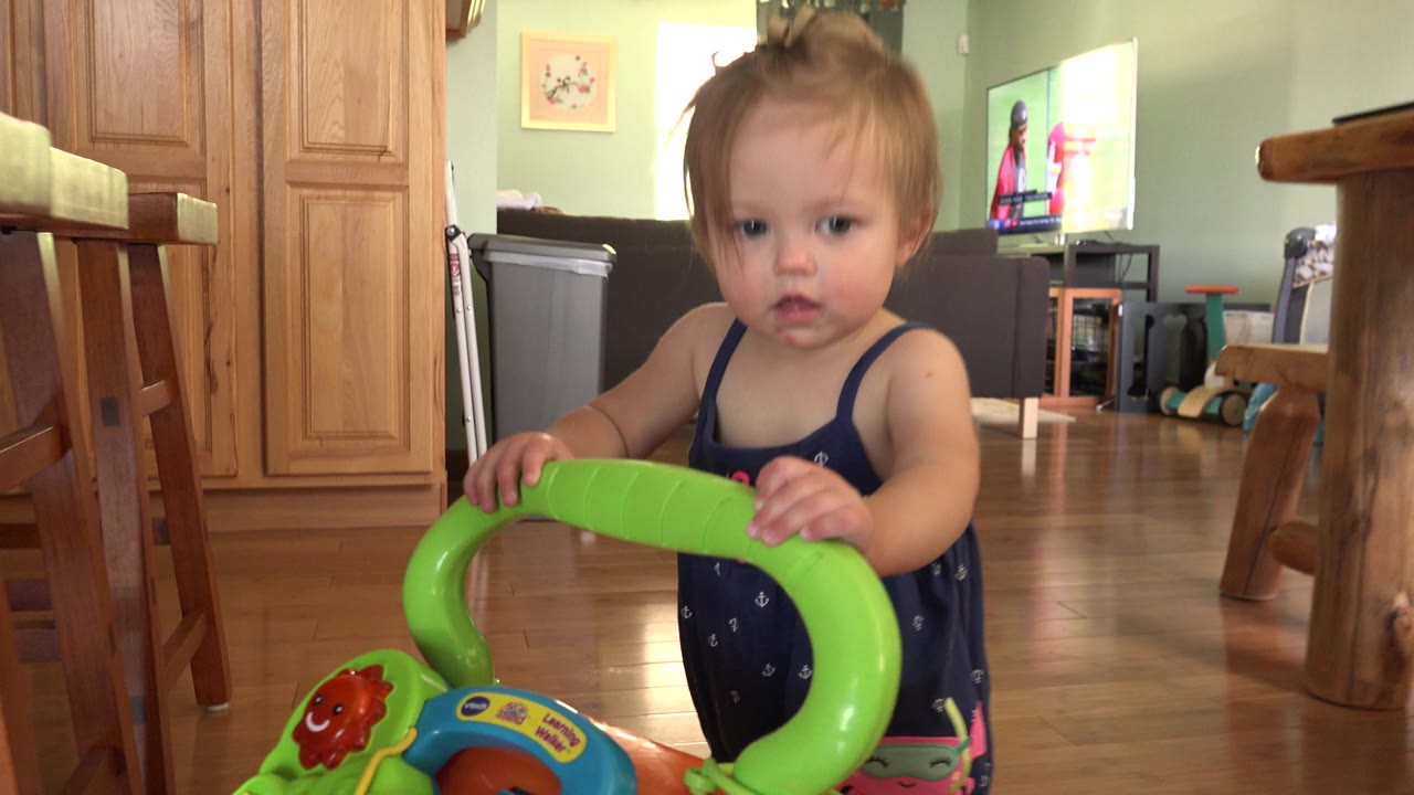 Baby faces the camera while holding a colorful push toy.