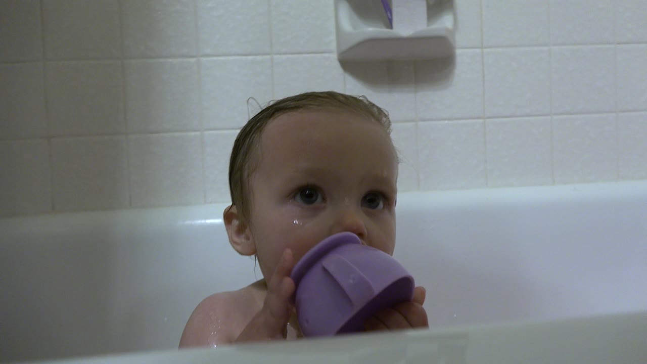 The baby boy remains in the Westminster bathroom tub, eyes turned upward while the purple cup rests against his mouth.