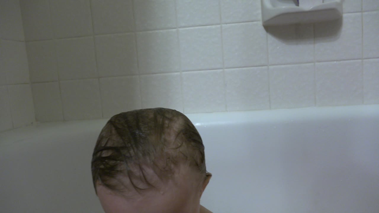 Baby's wet head peeking from a bathtub.