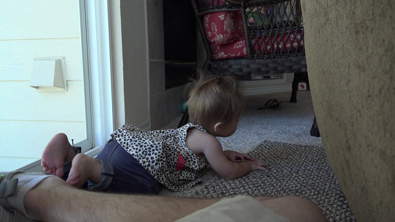 Young child crawling on carpet near a sliding glass door.