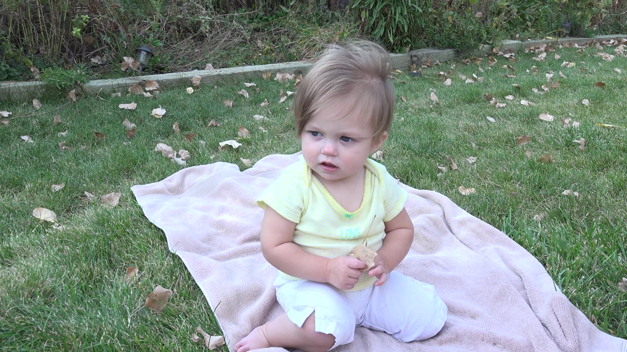 Baby looking right while seated on the blanket.
