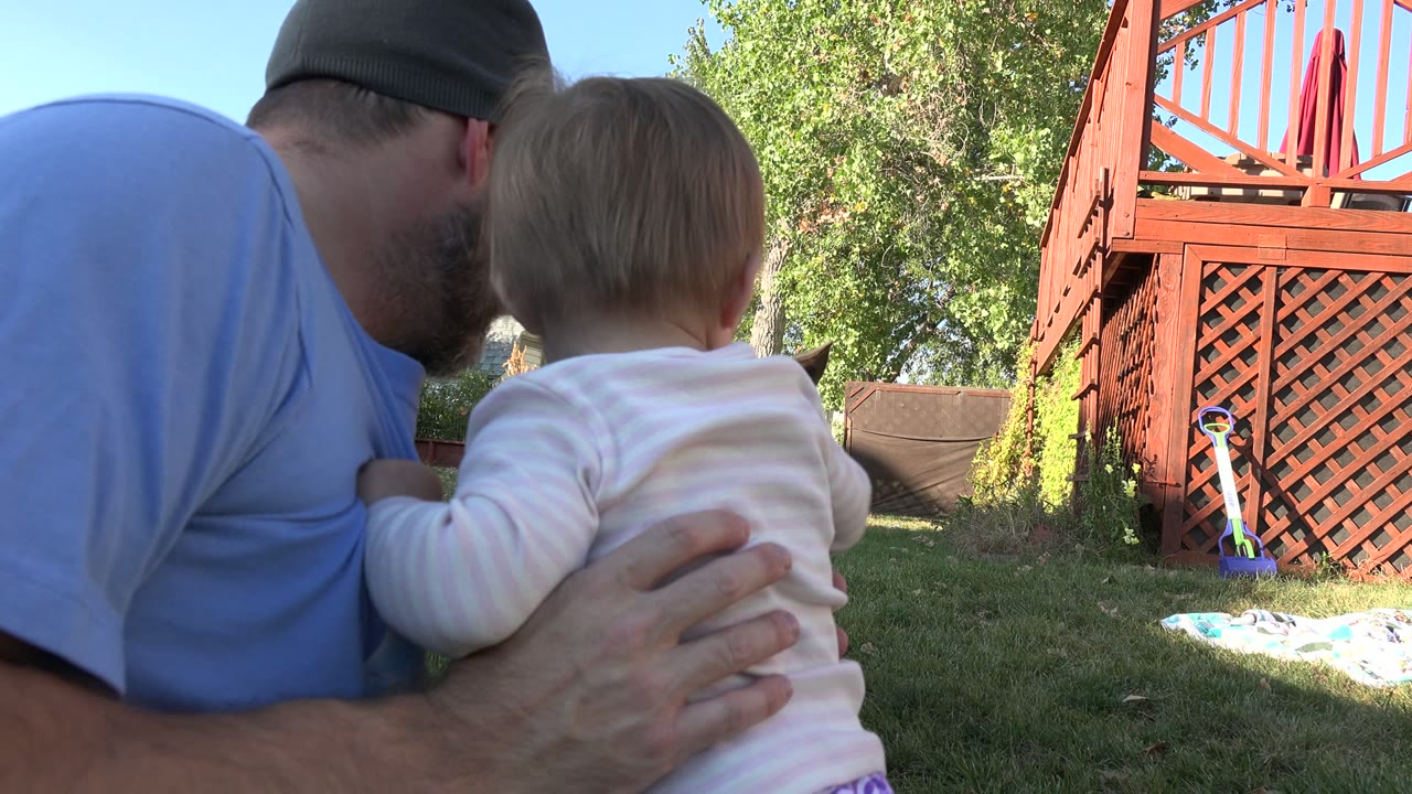 Father holds baby close while facing the backyard dog.