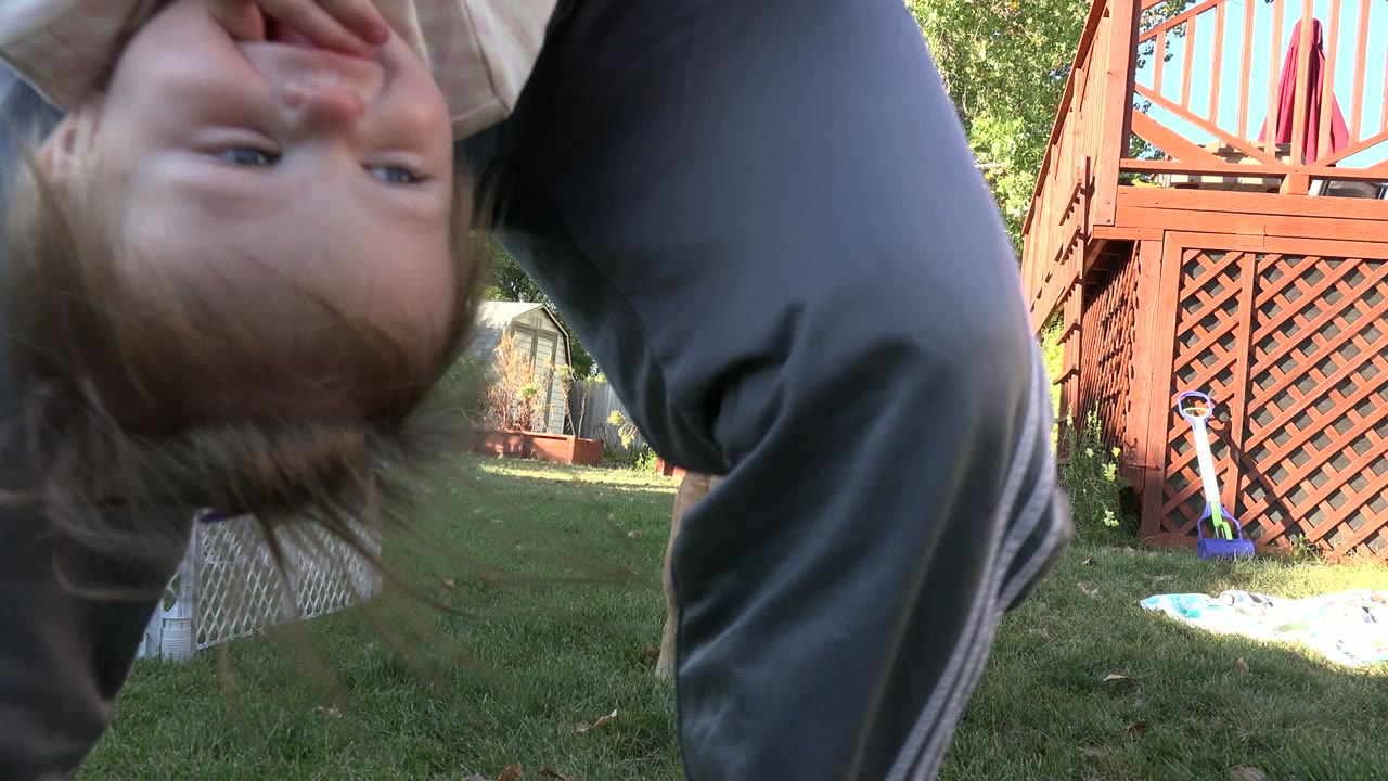 The child's upside-down face fills more of the frame while an adult stands over the ground camera in the Westminster, Colorado yard.