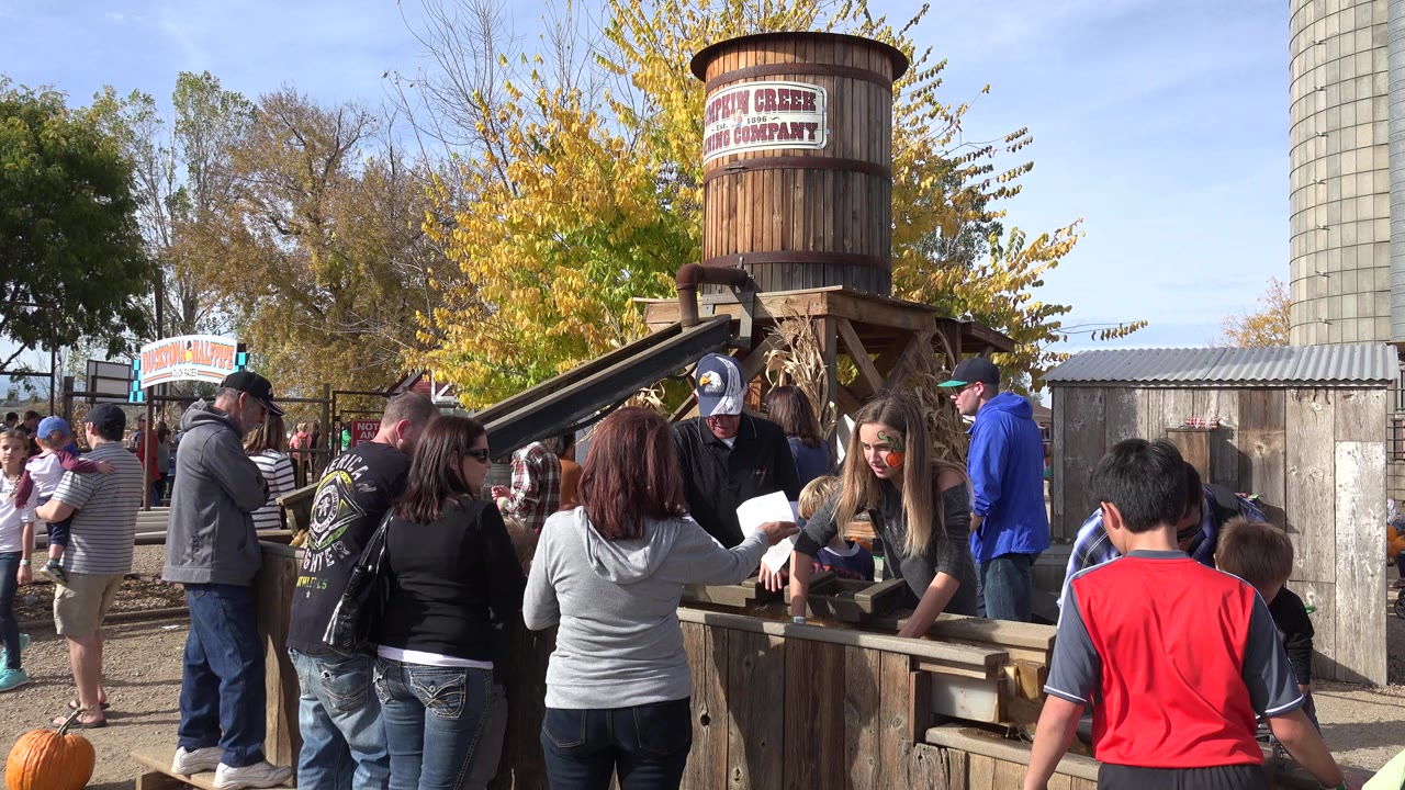 Crowd gathered around a wooden activity station outdoors.