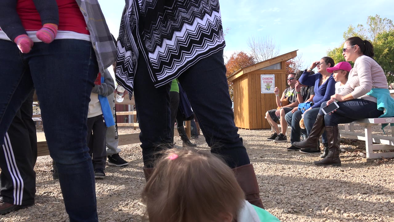 Toddler near adult legs at an outdoor gathering.