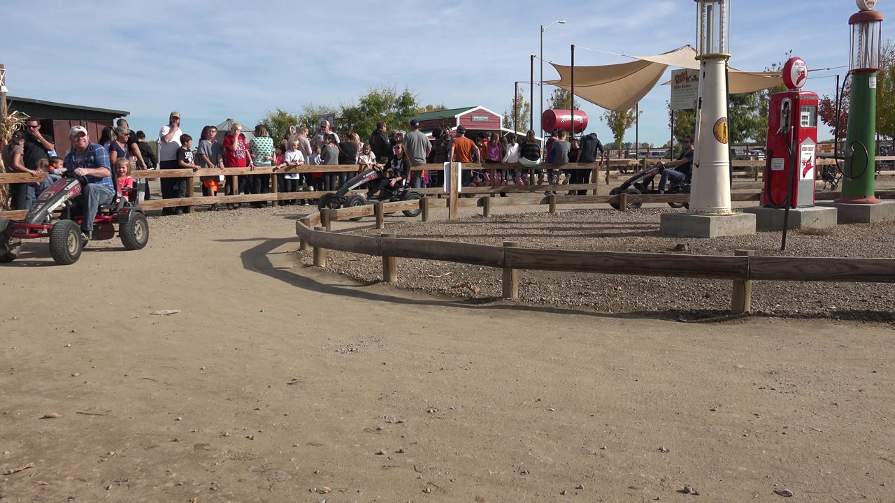 A man rides a pedal go-kart past spectators and ride decor.