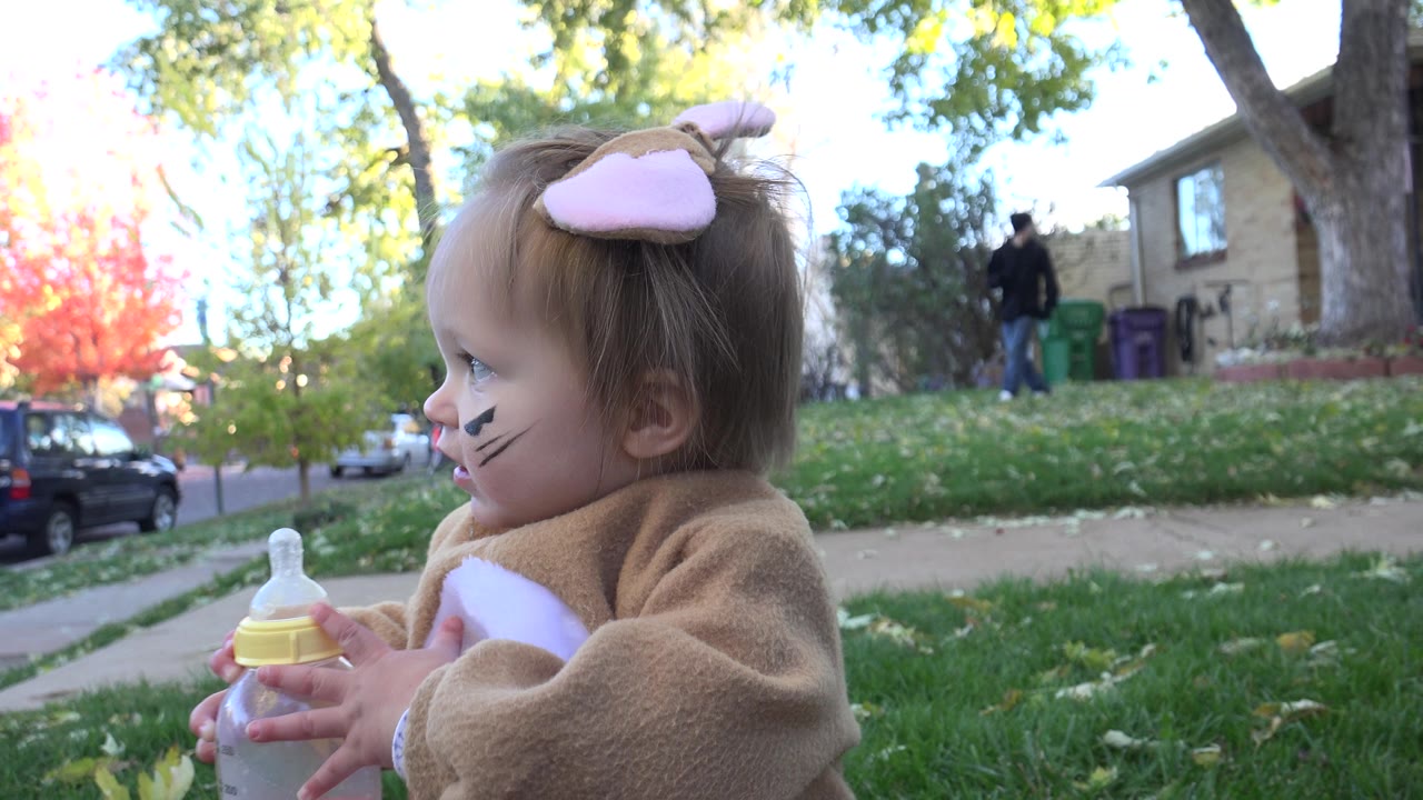 Toddler in rabbit costume holding a clear bottle in profile.
