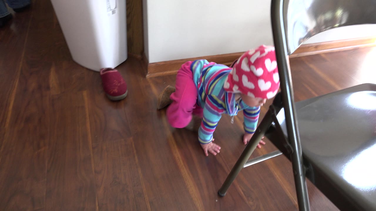 Baby on hands and knees beside a folding chair.