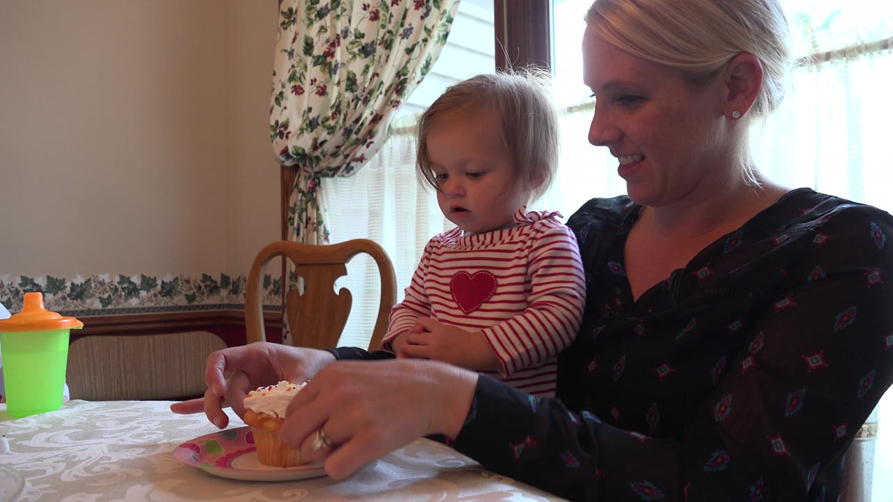 Toddler and mother look at a cupcake on the table.