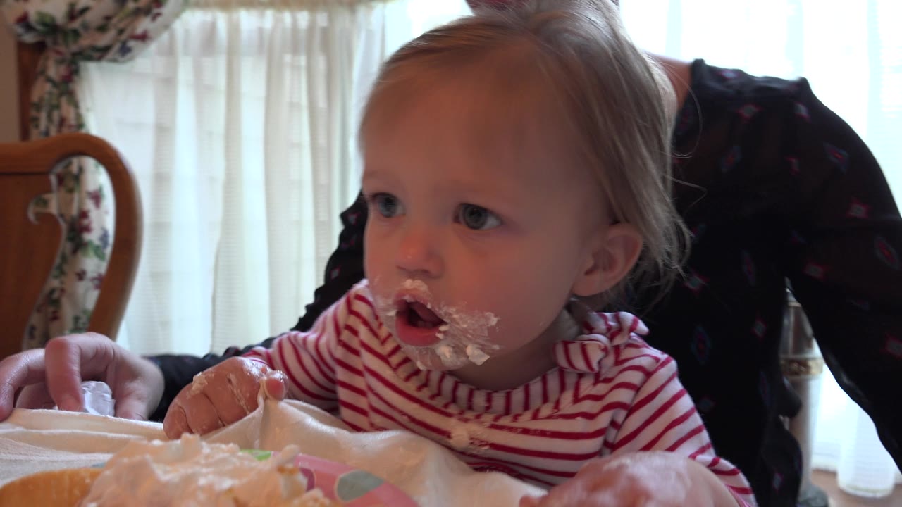 Toddler leans forward at a table with cream on their face.