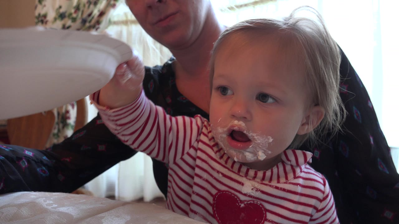 In Prairie Grove, Illinois, the child looks to the side with cream on the face while a small hand lifts near the white plate held at the left edge.