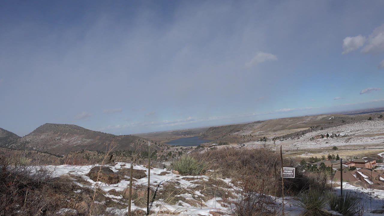 Early frame in Golden, Colorado, showing the fenced snowy foreground, brown scrub, distant water, rolling hills, and no visible people.