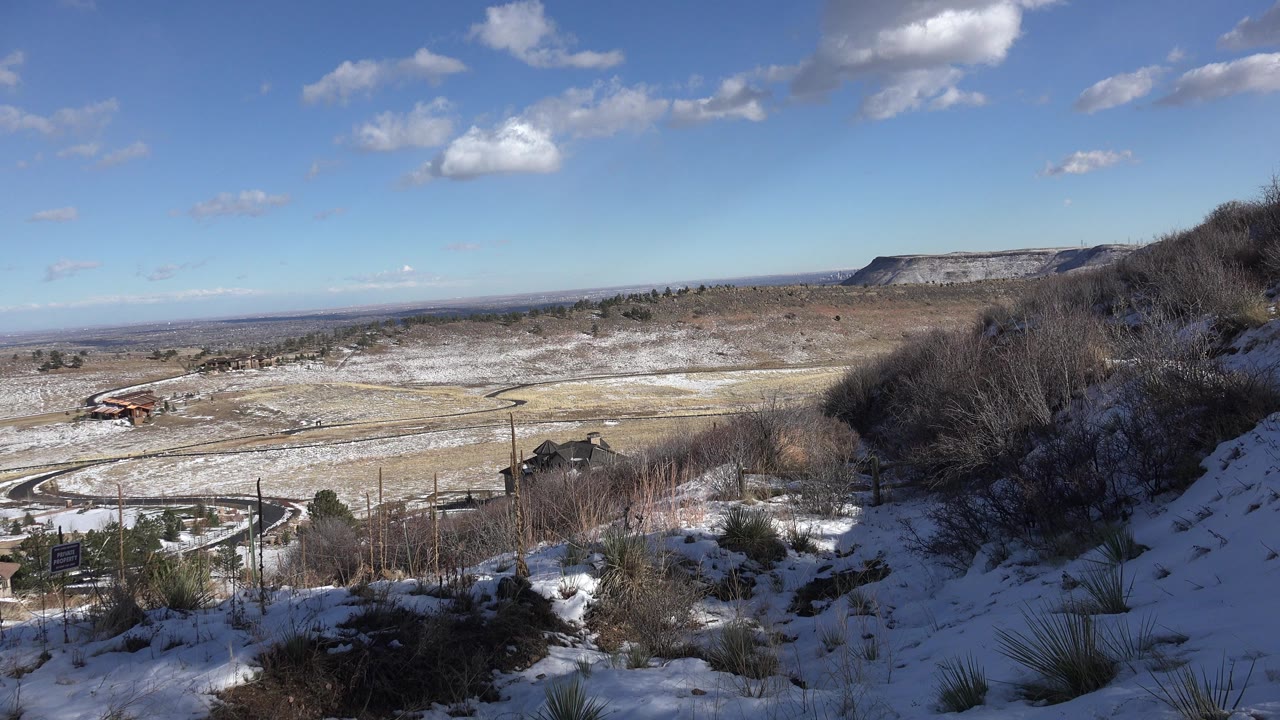 Snowy hillside view over a winding road and distant mesas