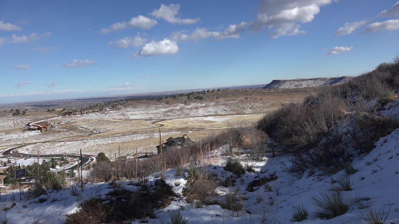 Snowy hillside overlooking a broad valley under a blue sky.