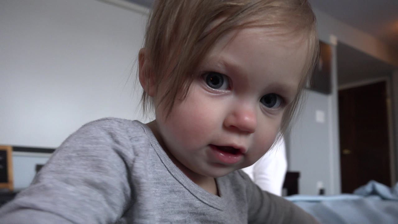 Blond toddler close to the camera in a home interior.