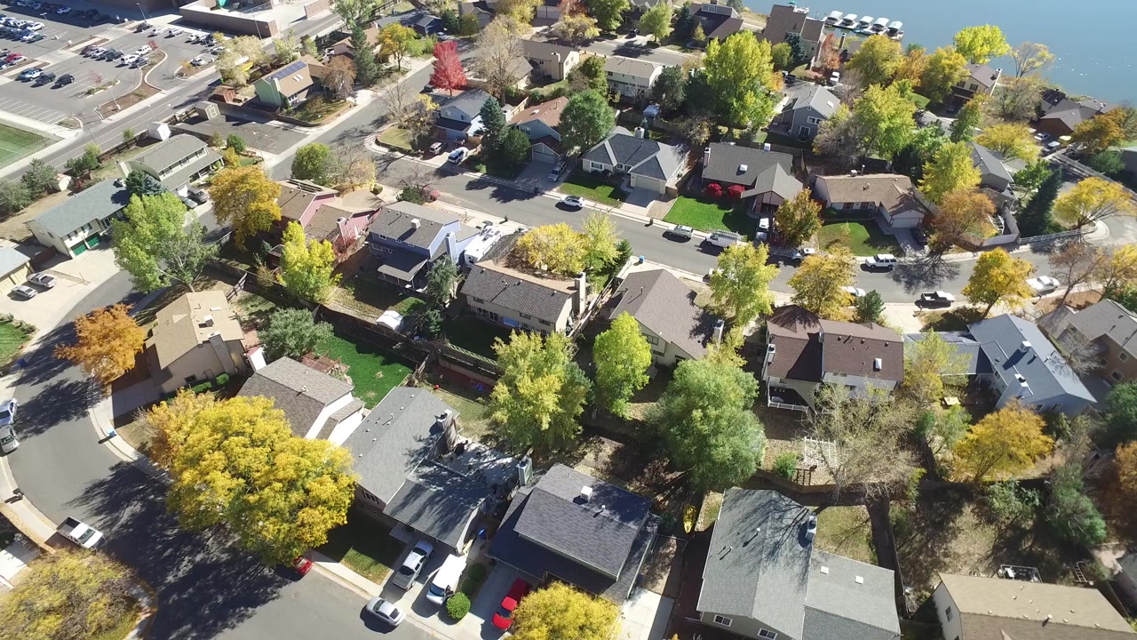 Overhead drone frame of Hidden Lake, Colorado homes with curved streets, driveways, autumn trees, parked cars, and no visible people.