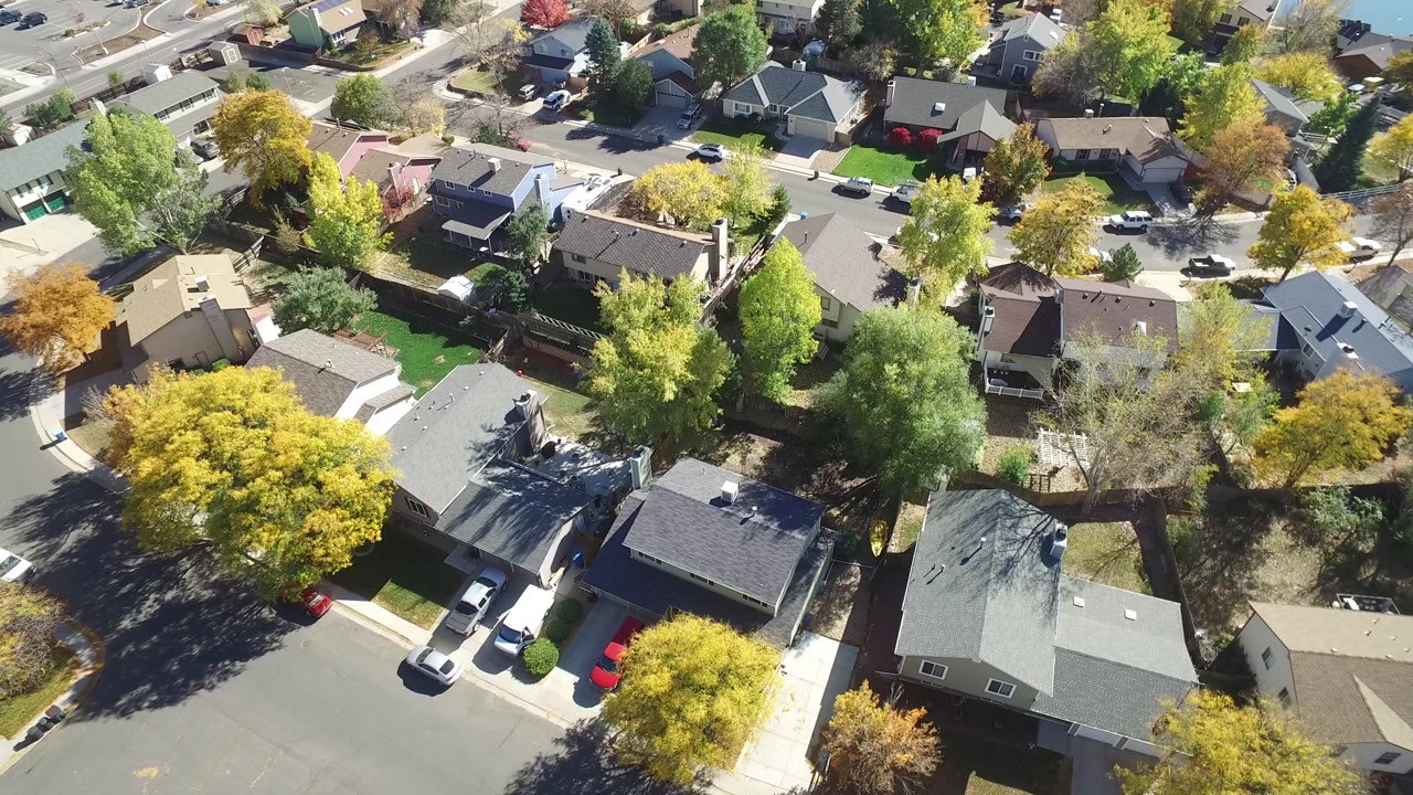 Overhead residential street with houses, trees, and parked cars.