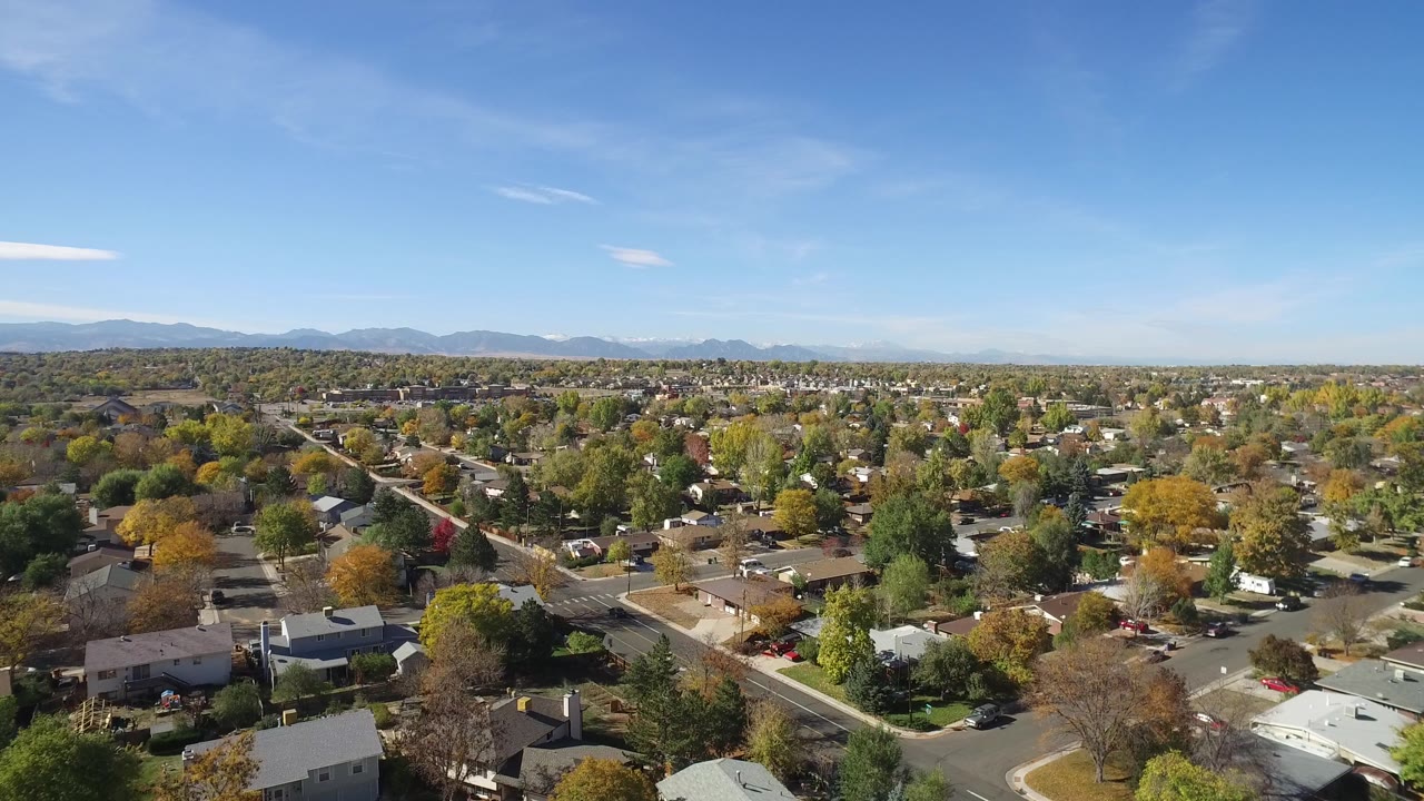 Hidden Lake, Colorado appears from above with tree-lined streets, light-colored rooftops, scattered cars, a broad suburban area, and no clearly visible people.