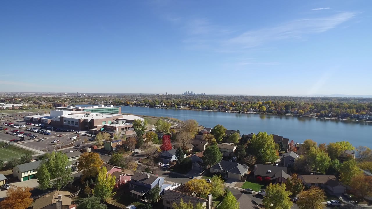 Drone-style view of a waterfront suburb with large building, homes, and trees.
