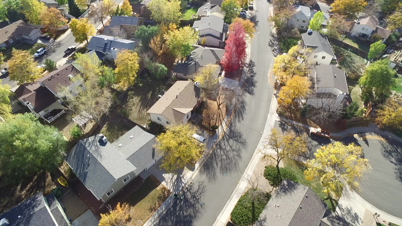Aerial view of homes, curved streets, and autumn trees.