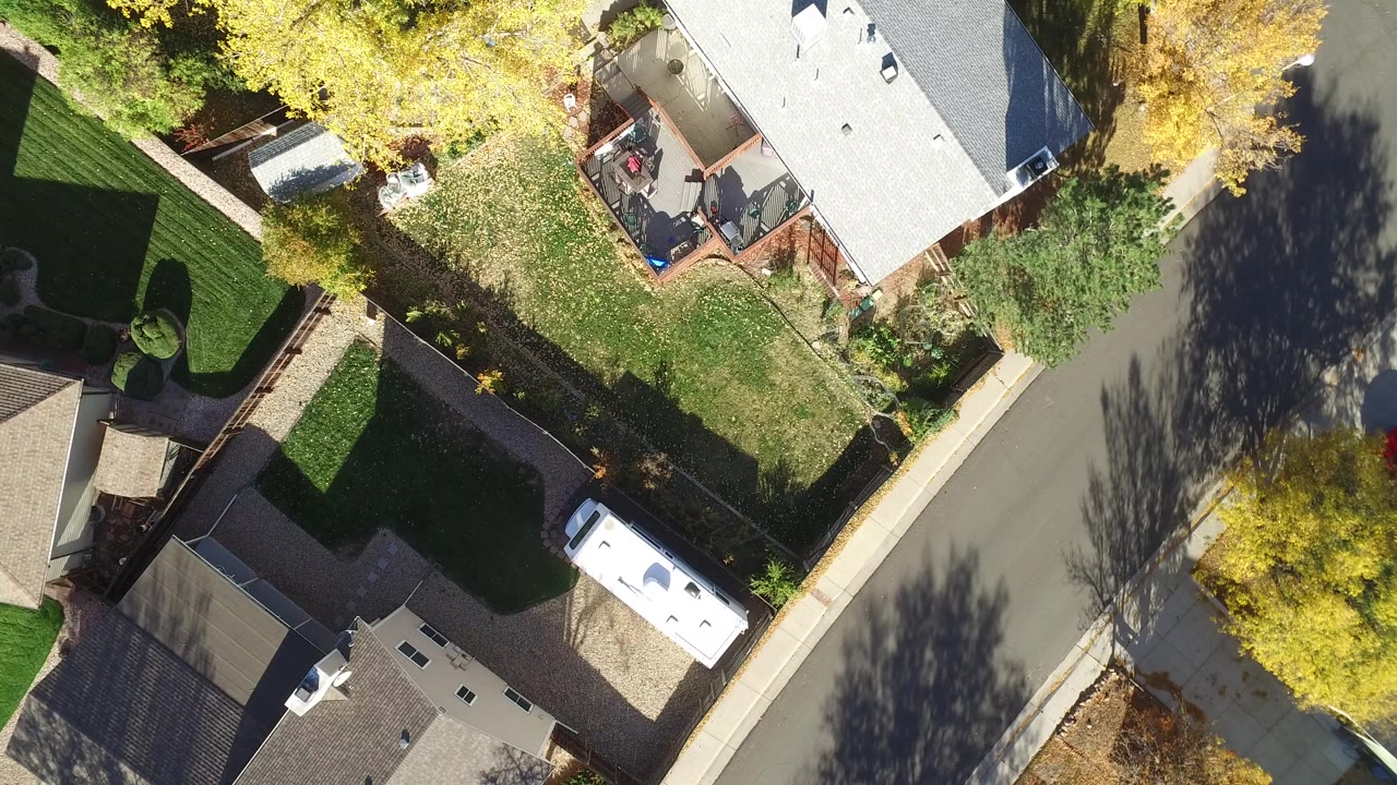 Overhead view of homes, yards, a curved street, and autumn trees.