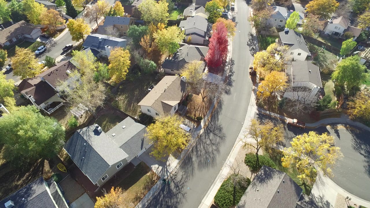 Aerial view of houses, a curving road, and autumn trees