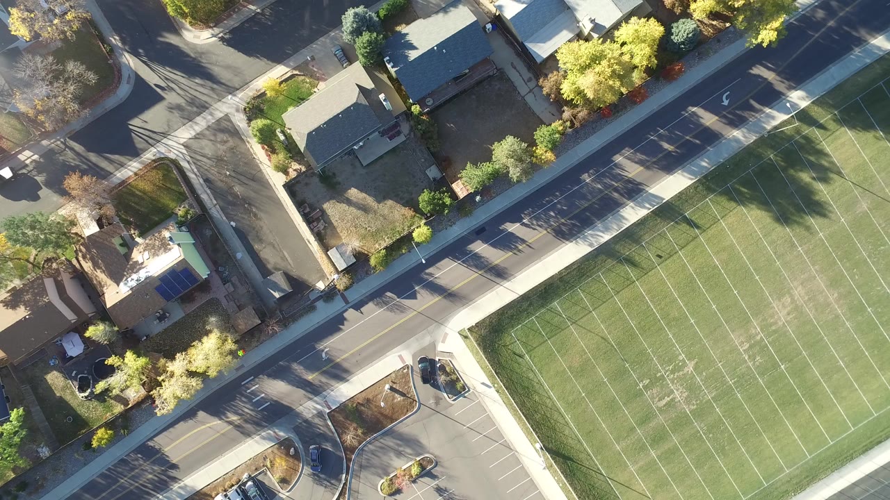 Overhead view of a lined football field beside roads and homes.