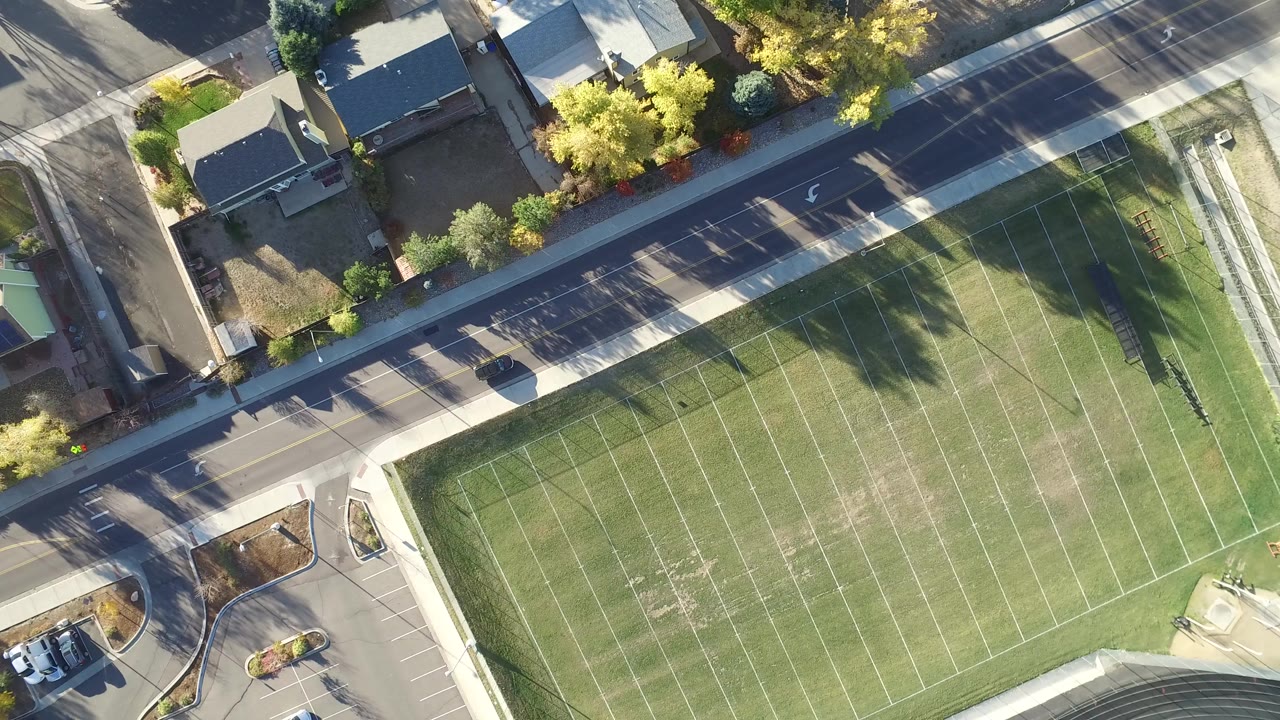 Overhead view of a football field beside a road and homes.