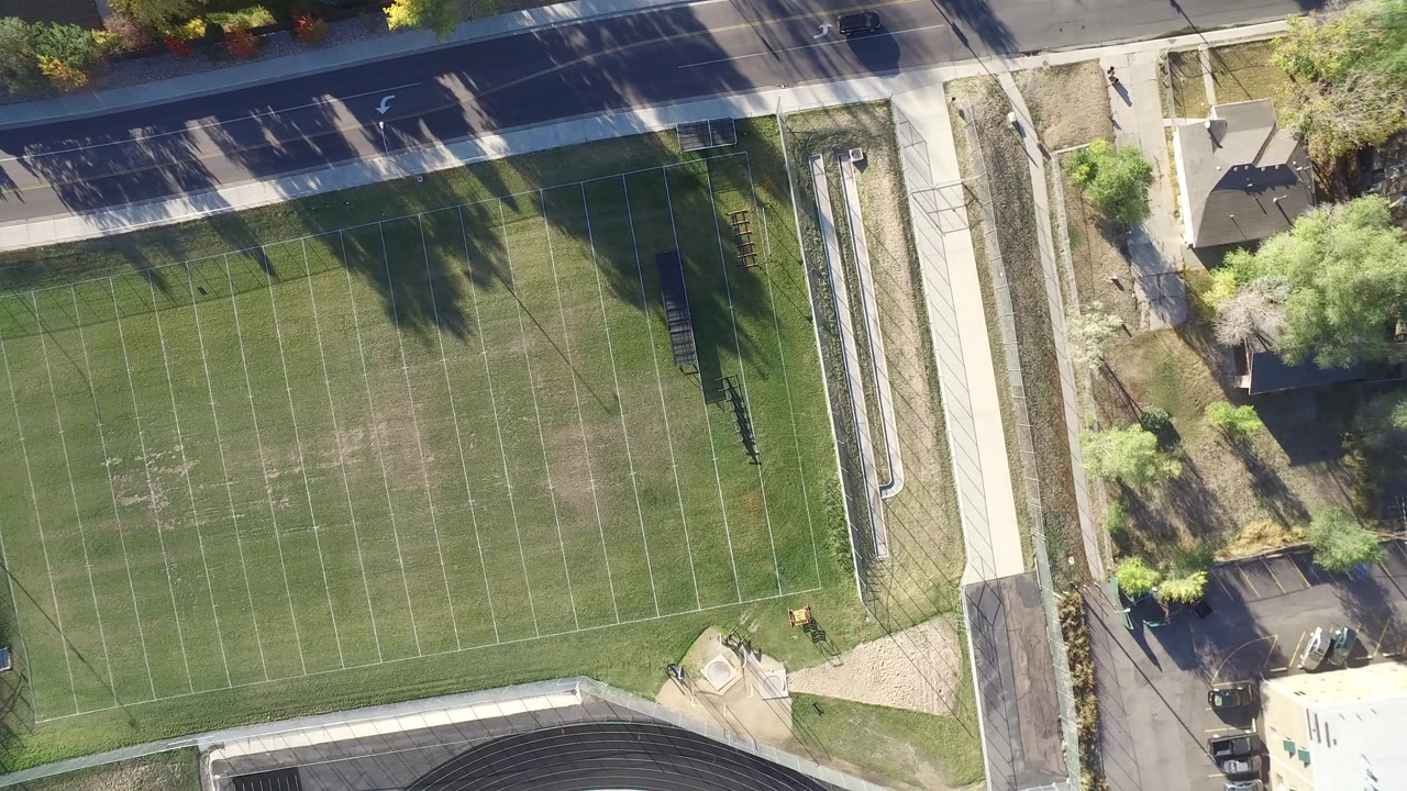 Overhead view of a green lined field beside a road and sidewalk.
