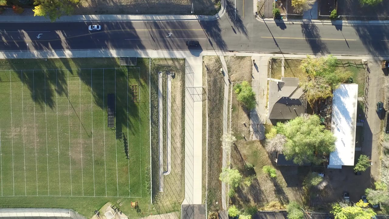 Overhead view of a tennis court beside a road and homes.
