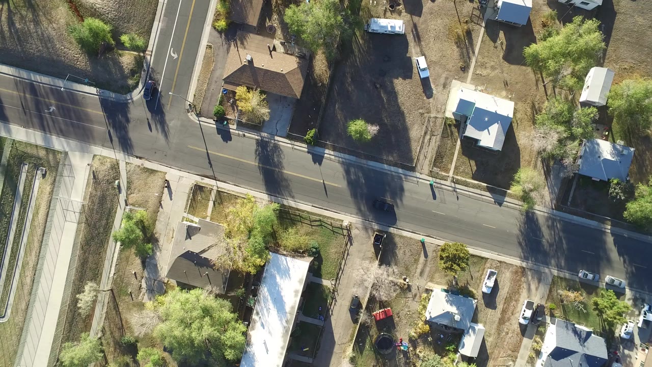 Overhead view of residential streets, houses, yards, trees, and parked vehicles.