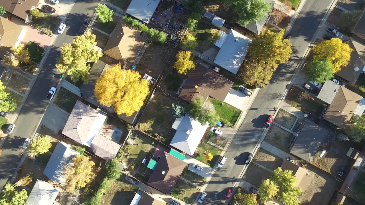 Aerial view of a residential street lined with homes, cars, and trees.