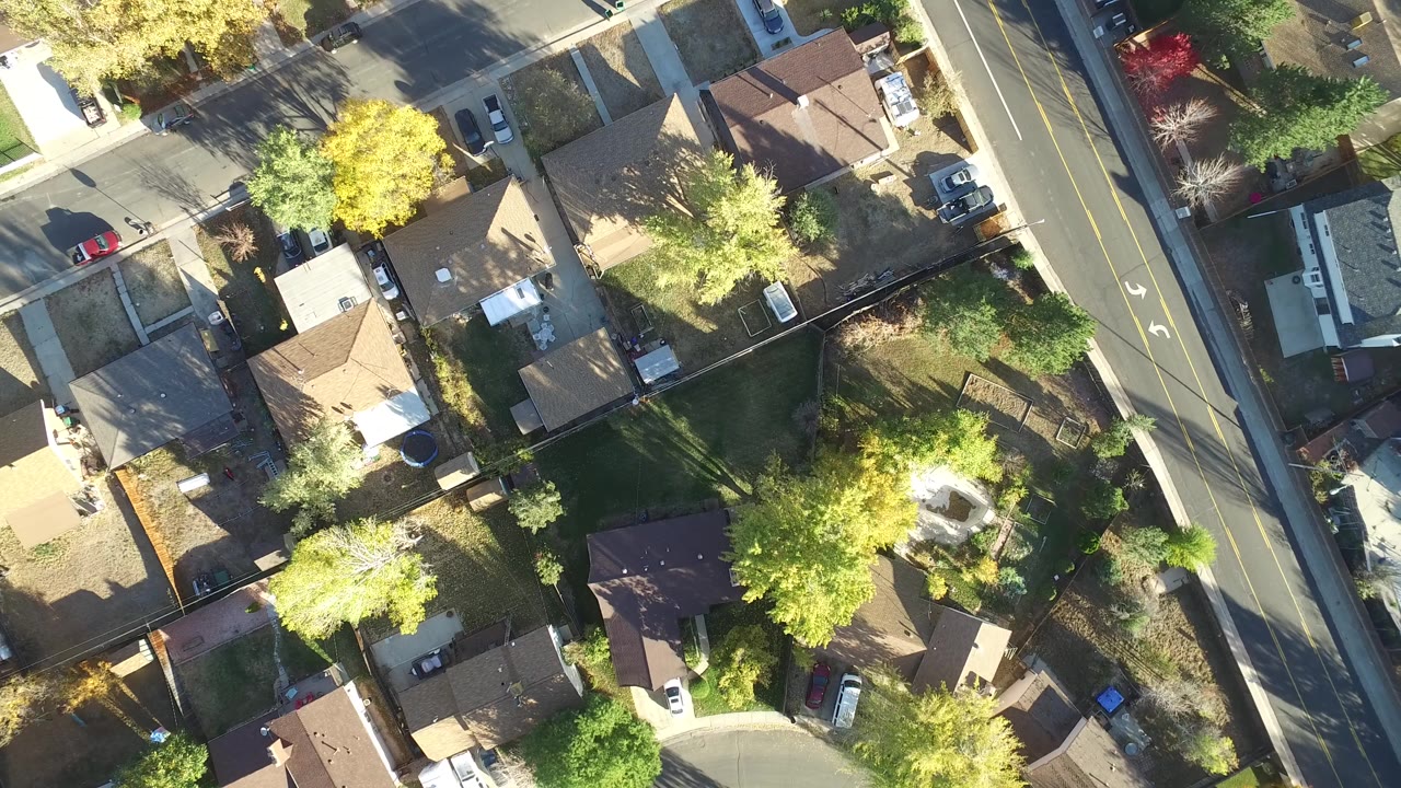Overhead view of homes, yards, trees, and a two-lane road