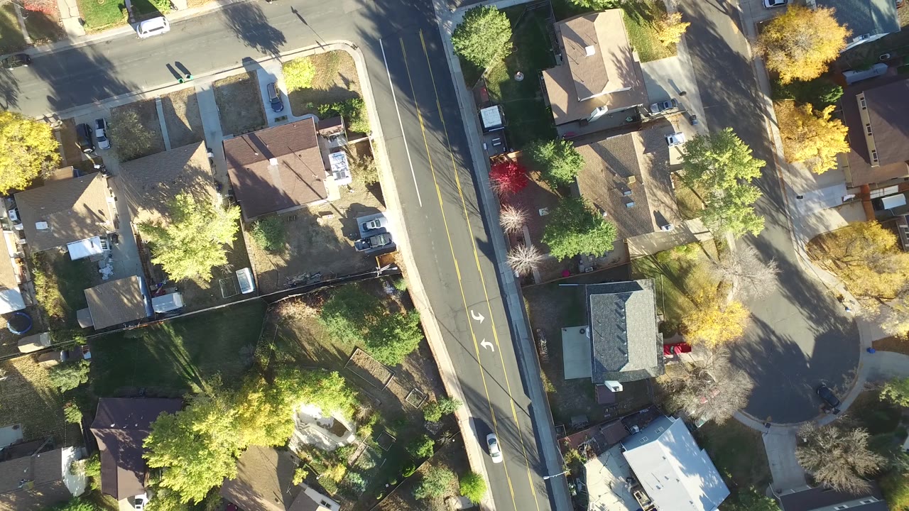 High overhead view in Hidden Lake, Colorado with a cul-de-sac area, fenced yards, rooftops, yellow trees, parked vehicles, and no visible people.