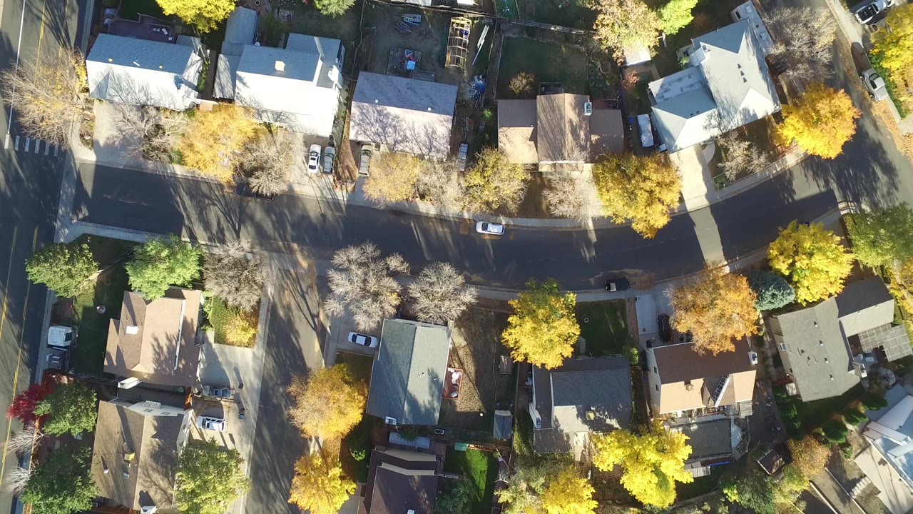 Top-down aerial frame over Hidden Lake, Colorado homes with curving residential streets, parked cars, and yellow trees, with no visible people.