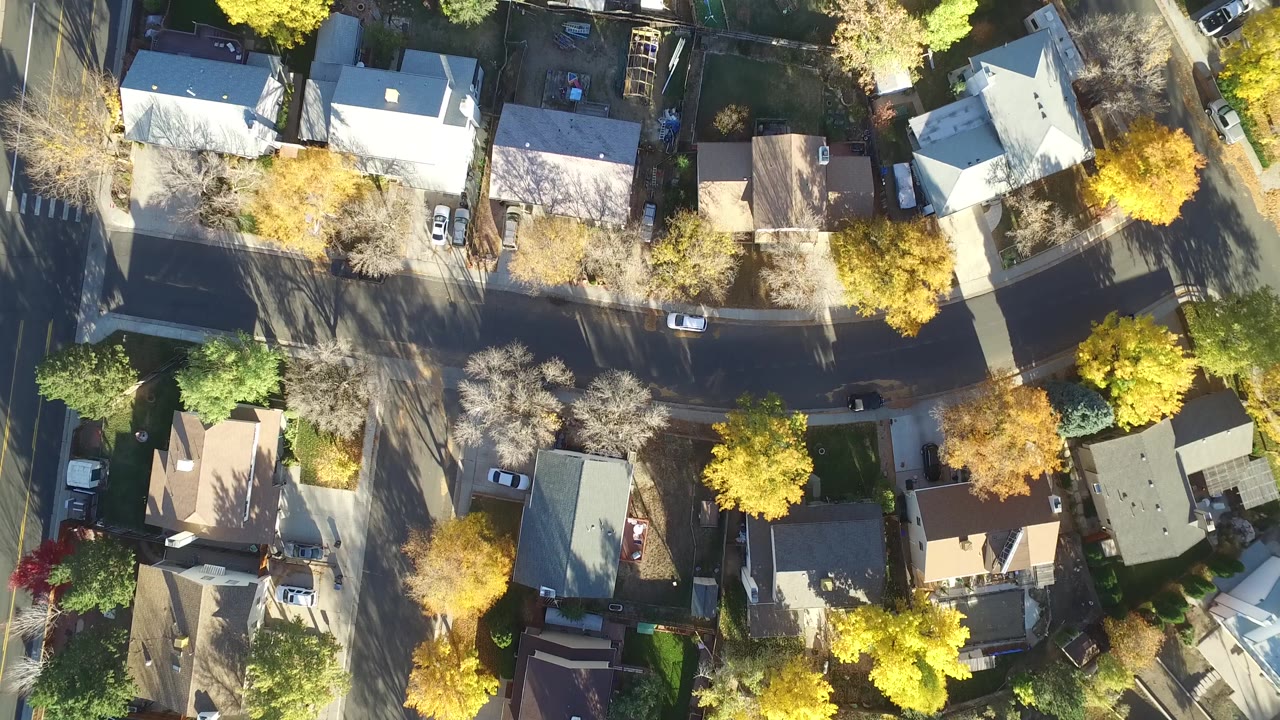 Aerial frame over Hidden Lake, Colorado showing detached homes, fenced yards, street edges, and mixed yellow and green tree cover, with no visible people.