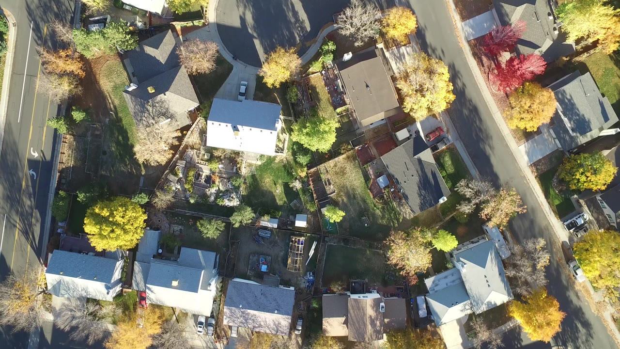 Overhead view of houses, streets, yards, and autumn trees.