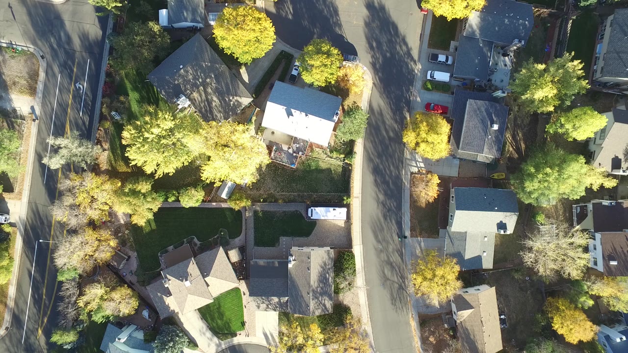 Aerial view over Hidden Lake, Colorado rooftops and adjoining streets, with bright sun on yellow trees and no visible people in the frame.